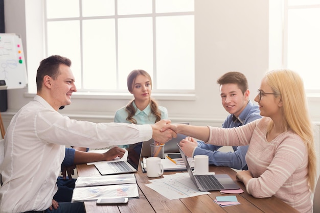 Business handshake at office corporate meeting, contract conclusion and successful agreement concept. Cheerful businessman and businesswoman hands meet, copy space