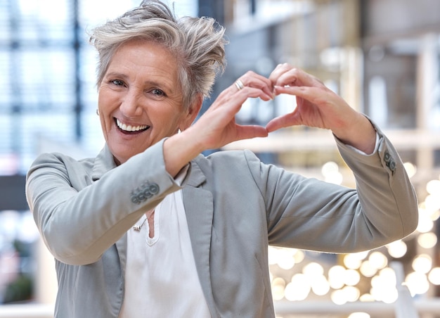 Business heart and hands with portrait of woman in office for support kindness and target Corporate goal and happy with senior female and positive gesture for success achievement and motivation