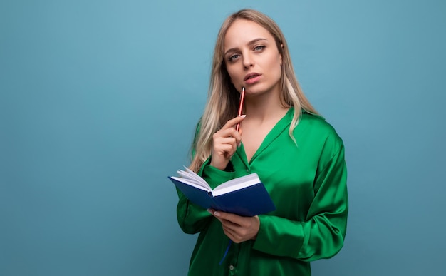 Business lady freelancer thinking about work holding notepad and pencil on blue bright background