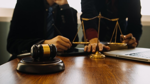 Business and lawyers discussing contract papers with brass scale on desk in office Law legal services advice justice and law concept picture with film grain effect