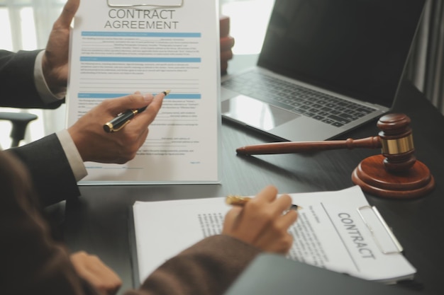 Business and lawyers discussing contract papers with brass scale on desk in office Law legal services advice justice and law concept picture with film grain effect