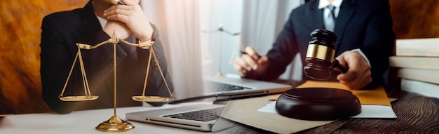 Business and lawyers discussing contract papers with brass scale on desk in office Law legal services advice justice and law concept picture with film grain effect