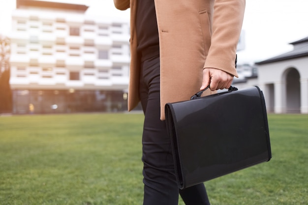 Business man in a brown coat and a bag with documents in his hands goes to wor