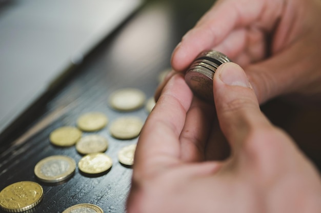 Photo business man counting money. rich male hands holds and count coins of different euros on table in front of a laptop