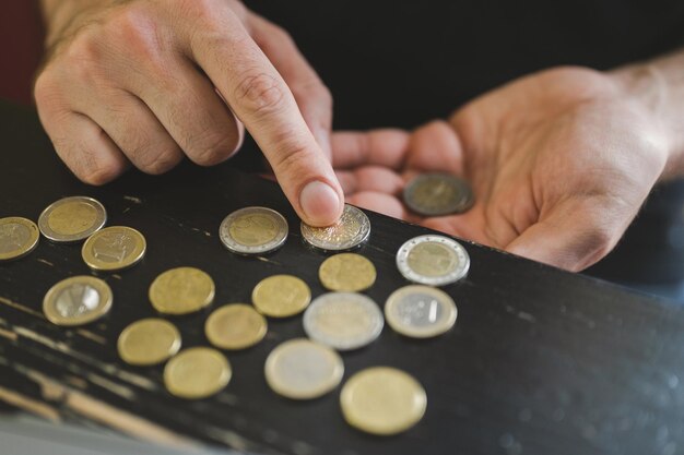 Photo business man counting money rich male hands holds and count coins of different euros on table