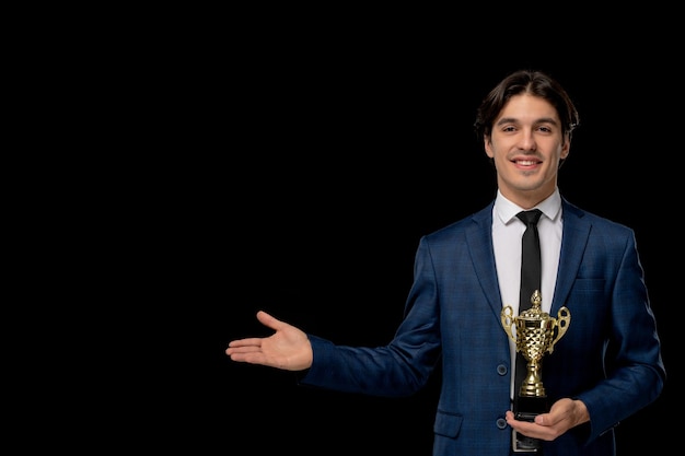 Business man cute handsome guy in dark blue suit with the tie smiling and holding trophy