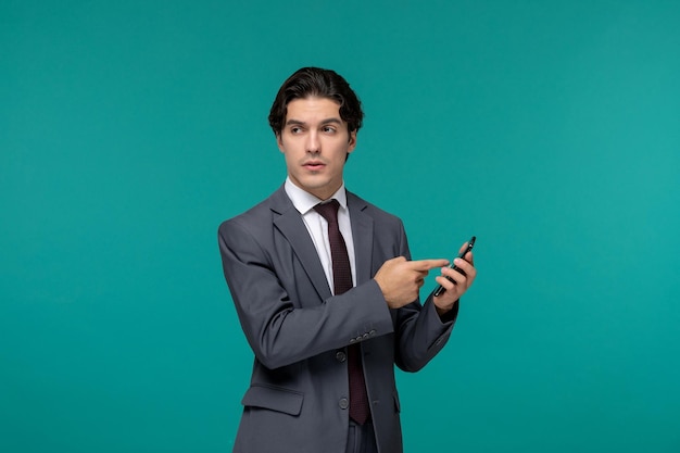 Business man cute young handsome man in grey office suit and tie pointing on phone