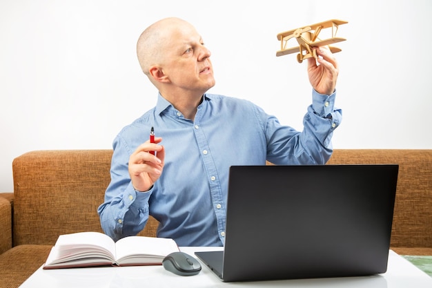 Business man dreams of his achievement Business dream concept A man holds a wooden airplane model in his hands