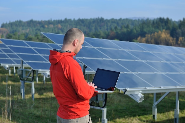 business man  engineer using laptop at solar panels plant eco energy field  in background