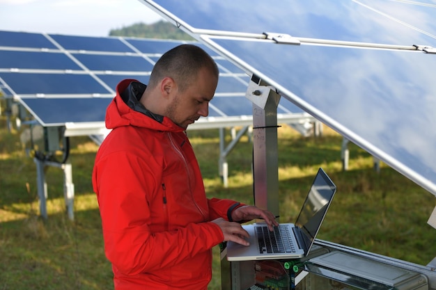 business man  engineer using laptop at solar panels plant eco energy field  in background