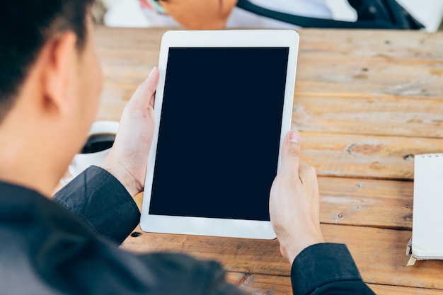 Business man hand holding tablet in coffee shop.