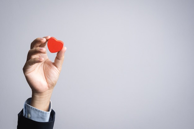 Business man hand with wooden red heart object