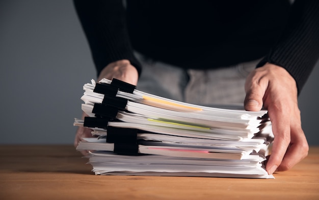 Business man holding stack of papers.