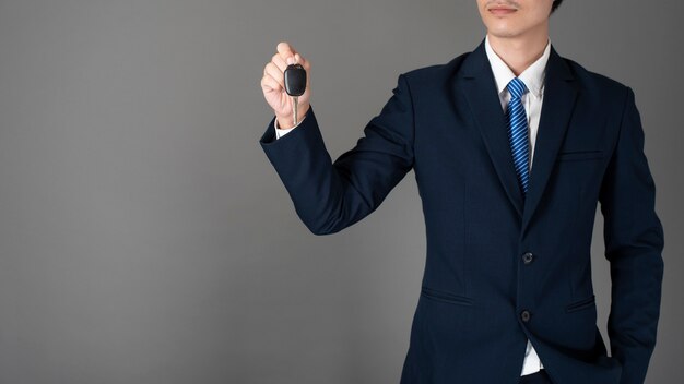 Photo business man is holding car key, grey background in studio