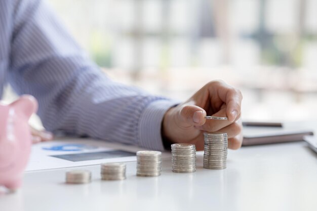 Business man is stacking coins on top of the coin pile on the highest row Placing coins in a row from low to high is comparable to saving money to grow more Money saving ideas for investing in funds