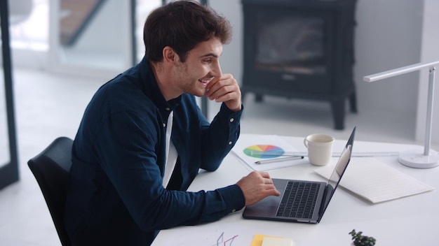 Business man looking documents on laptop Smiling guy analyzing financial charts