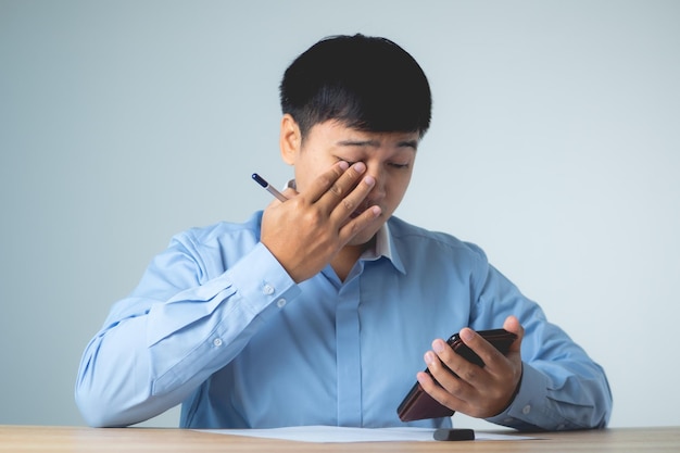 Business man pains his eyes when he watches a mobile phone too much He presses on his eye by hands Ophthalmology concept This shot is medium close up portrait