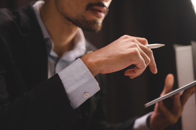 Business man person using a pen to sign a agreement document paper to approve by signature hand of businessman working on finance lawyer contract paperwork in office concept of deal on business desk