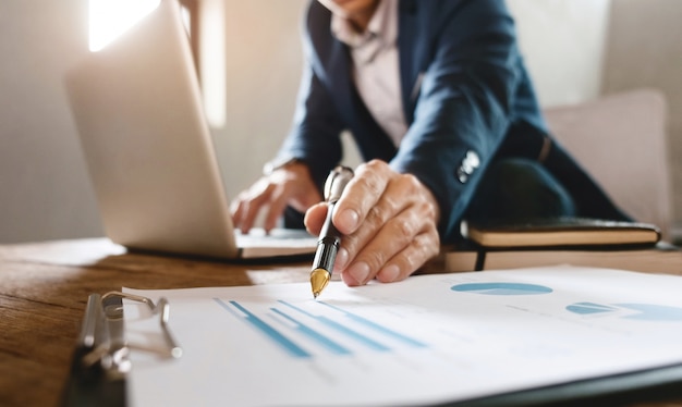 business man pointing at business document with laptop at a workplace