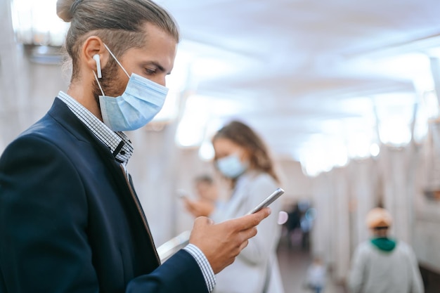 Business man in a protective mask waiting for a train in the subway