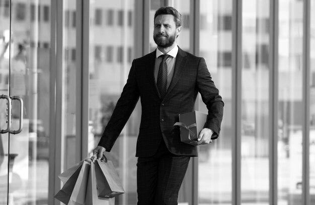 Photo business man shopping in a shopping center happy businessman in suit holding paperbags shopaholic