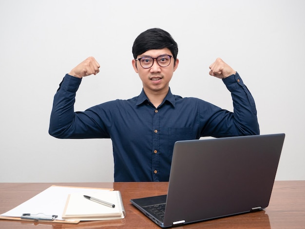 Business man sit at workplace gesture show muscle confident face