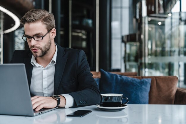 Business man sitting at his desk working on laptop and cup of coffee