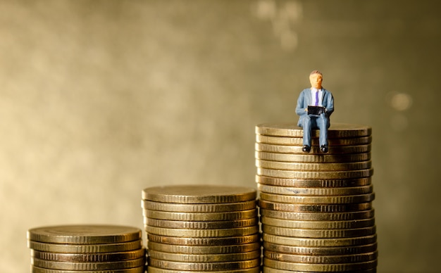 business man sitting on top of pile stack of golden coins