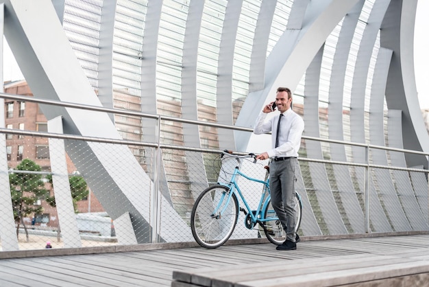 Business man standing by his vintage bicycle speaking on the mob