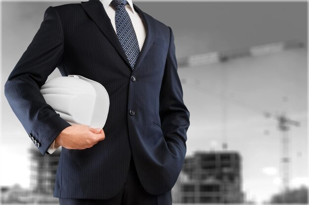 Business man in suit with helmet on grey background