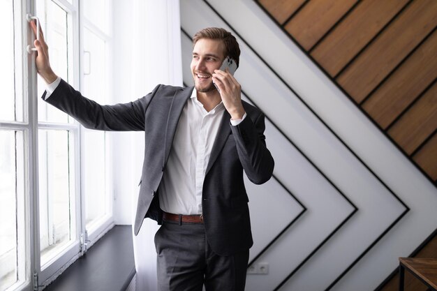 Business man talking on the phone in the office by the window