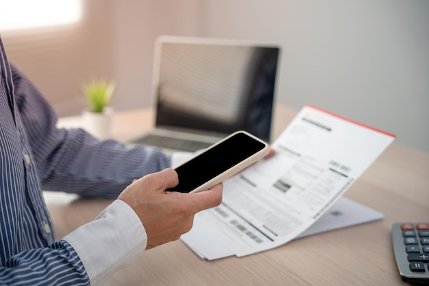 Business man uses his phone to scan a barcode to pay his monthly credit card bill after receiving an invoice online bill payment concept