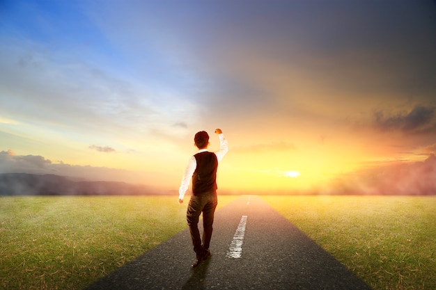 Business man walking on highway road with morning sunrise