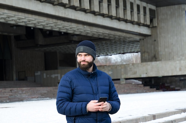 business man in winter casual clothes, jacket, hat. Walking in the city street, talking on the phone