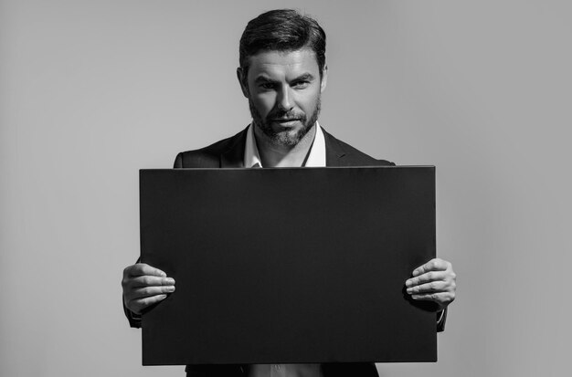 Photo business man with blank banner ad on studio background portrait of attractive man holding empty blank poster man showing blank poster male presenting signboard board or banner with copy space