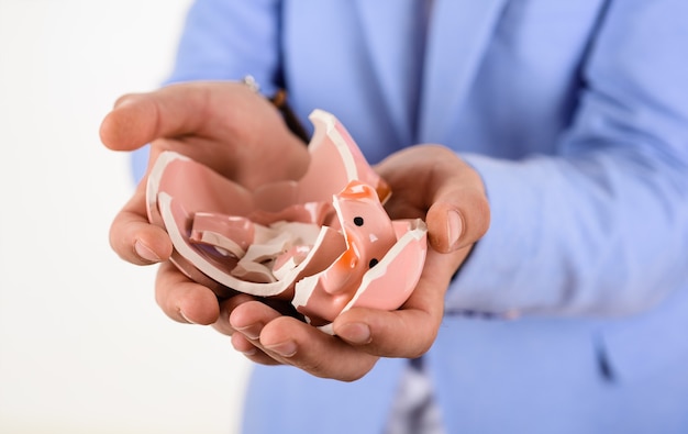 Business man with breaking piggy bank in hands selective focus businessman holds broken piggy bank