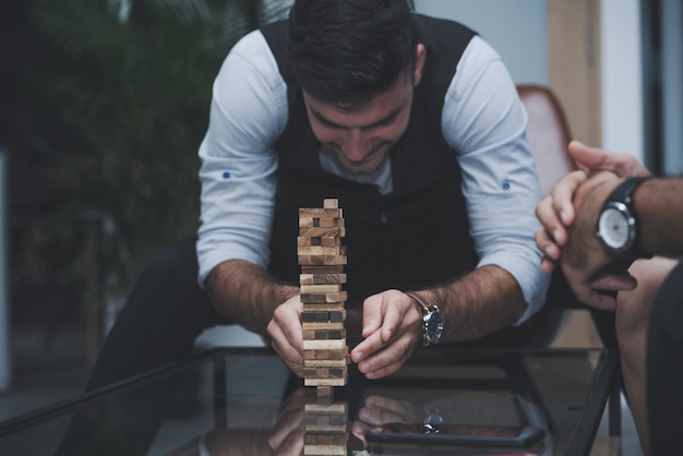 Photo business man with colleagues relaxing play wood blocks stacks game together in office