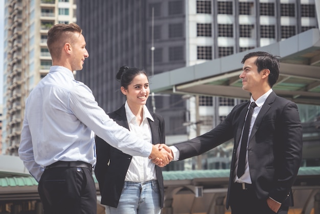 Business man with handshake with partner and woman cheering