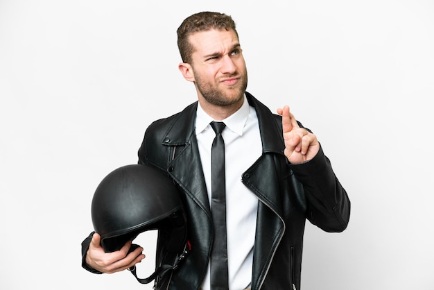 Business man with a motorcycle helmet over isolated white background with fingers crossing and wishing the best