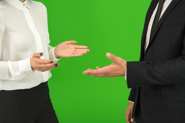 The business man and woman gesture on the green background