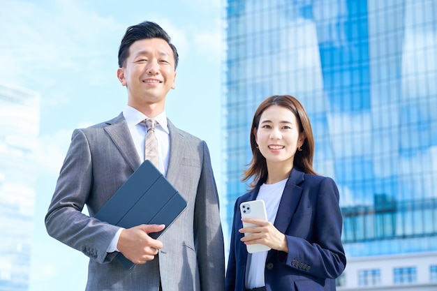 Business man and woman standing in front of skyscraper