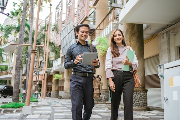 Business man and woman walking trough sidewalk smiling going to office