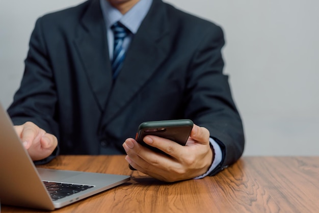 Business man working on laptop computer and using mobile phone on desk