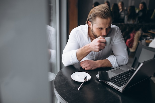 Business man working with laptop and drinking coffee in a cafe