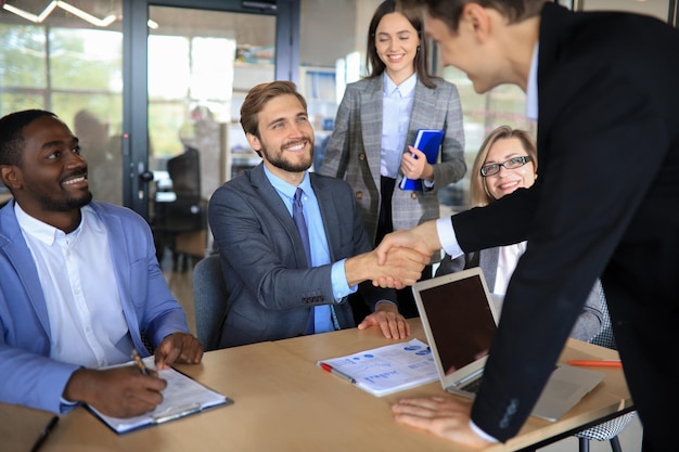 Business meeting associates shaking hands in office.