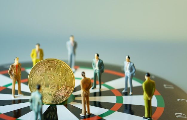 Business miniature people standing around bitcoin gold on dartboard hitting in the target center of dartboard Target business success and investment and finance concepts