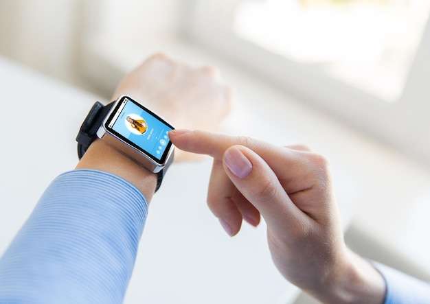 business, modern technology, media and people concept - close up of female hands setting smart watch with music player on screen at office