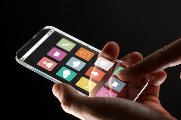 business, multimedia, people and modern technology concept - close up of businessman hand with transparent smartphone with menu icons on screen over black background