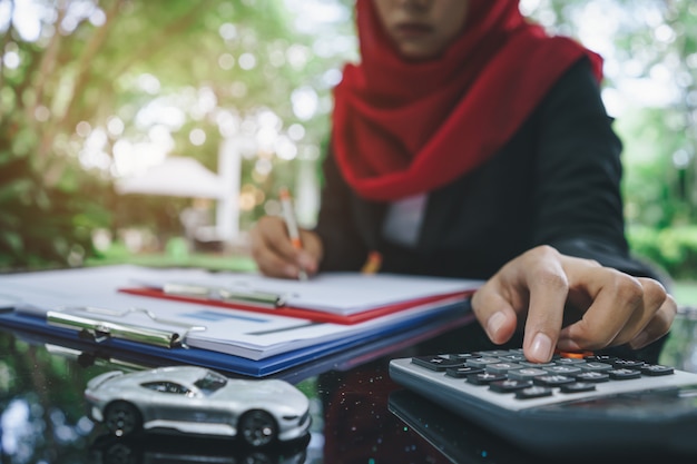 Business muslim woman hands writing and calculating car insurance quotes