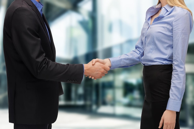 business and office concept - businessman and businesswoman shaking hands outdoors